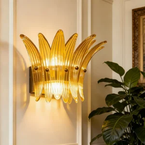 Amber fluted glass wall sconce mounted on paneled wall with warm illumination and potted plant styling