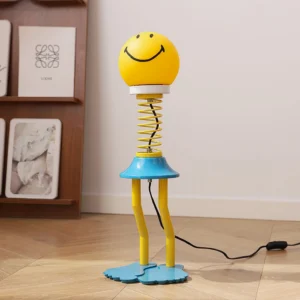 Smiley face spring lamp three-quarter angle on wooden shelf, yellow shade with blue barefoot base, home interior styling