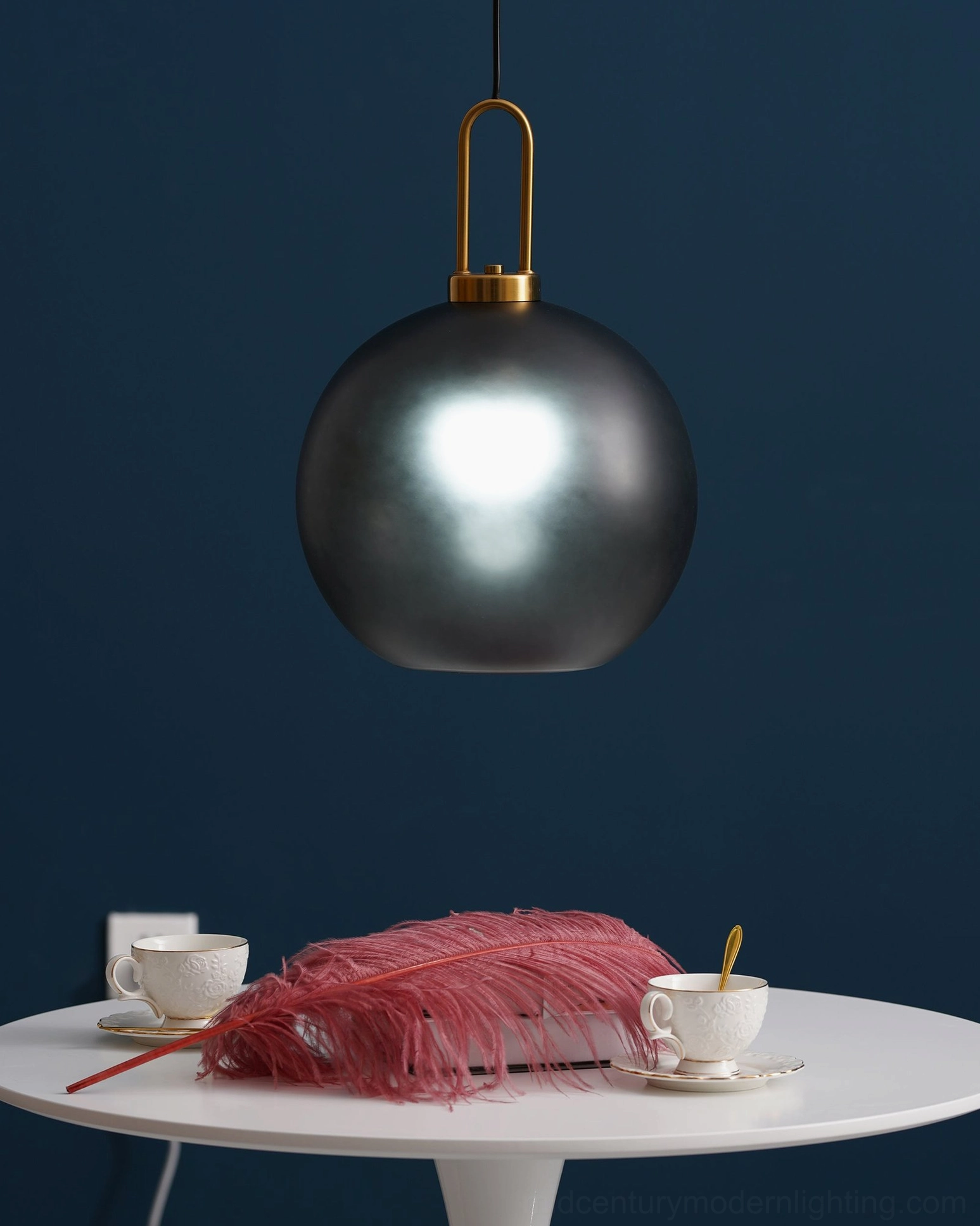 Dark gray globe pendant lamp in dining nook with pink feather table decor, brass metal hardware detail
