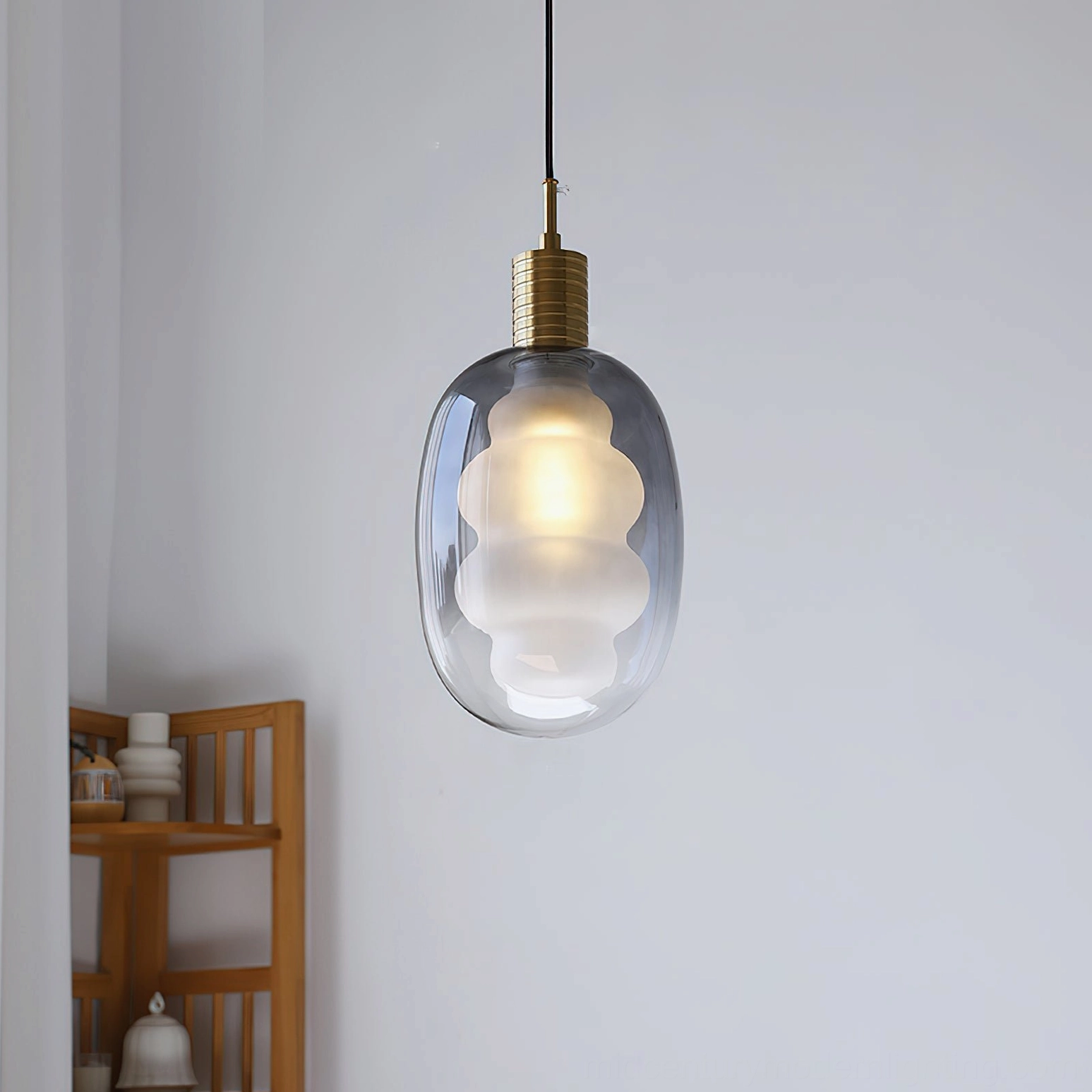 Smoky gray gradient glass pendant light on wooden display shelf, brass metal fixture, contemporary lighting