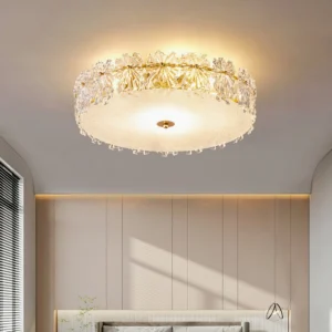 Low angle upward view of round crystal ceiling lamp installed in warm modern master bedroom, showing gold hardware and frosted glass diffuser details