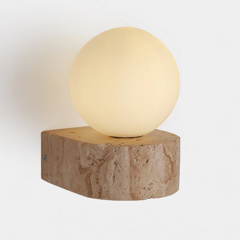 Solace wall sconce illuminated showing warm glow through frosted glass and marbled stone base