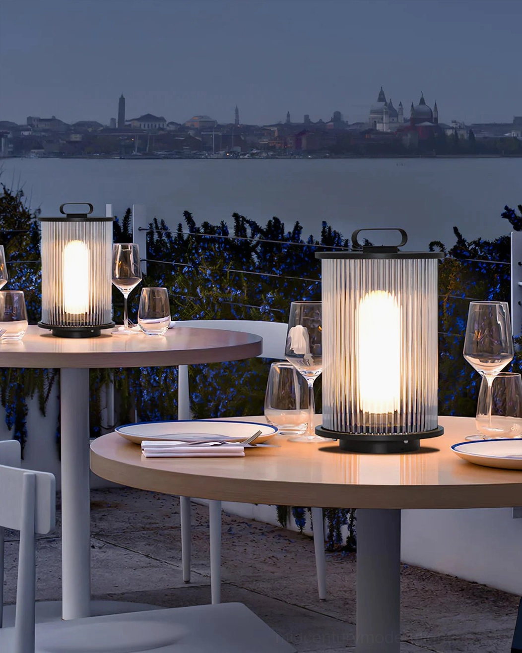 Solar dining lanterns with warm ambient glowing light on waterfront outdoor dining terrace table