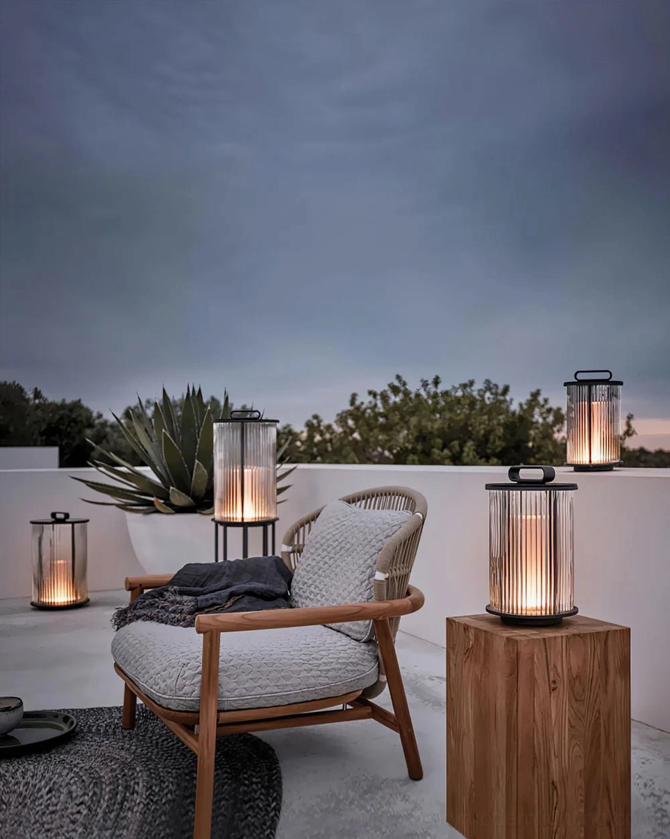 Solar glass lantern table lamps on side table and wooden pedestal in outdoor patio lounge