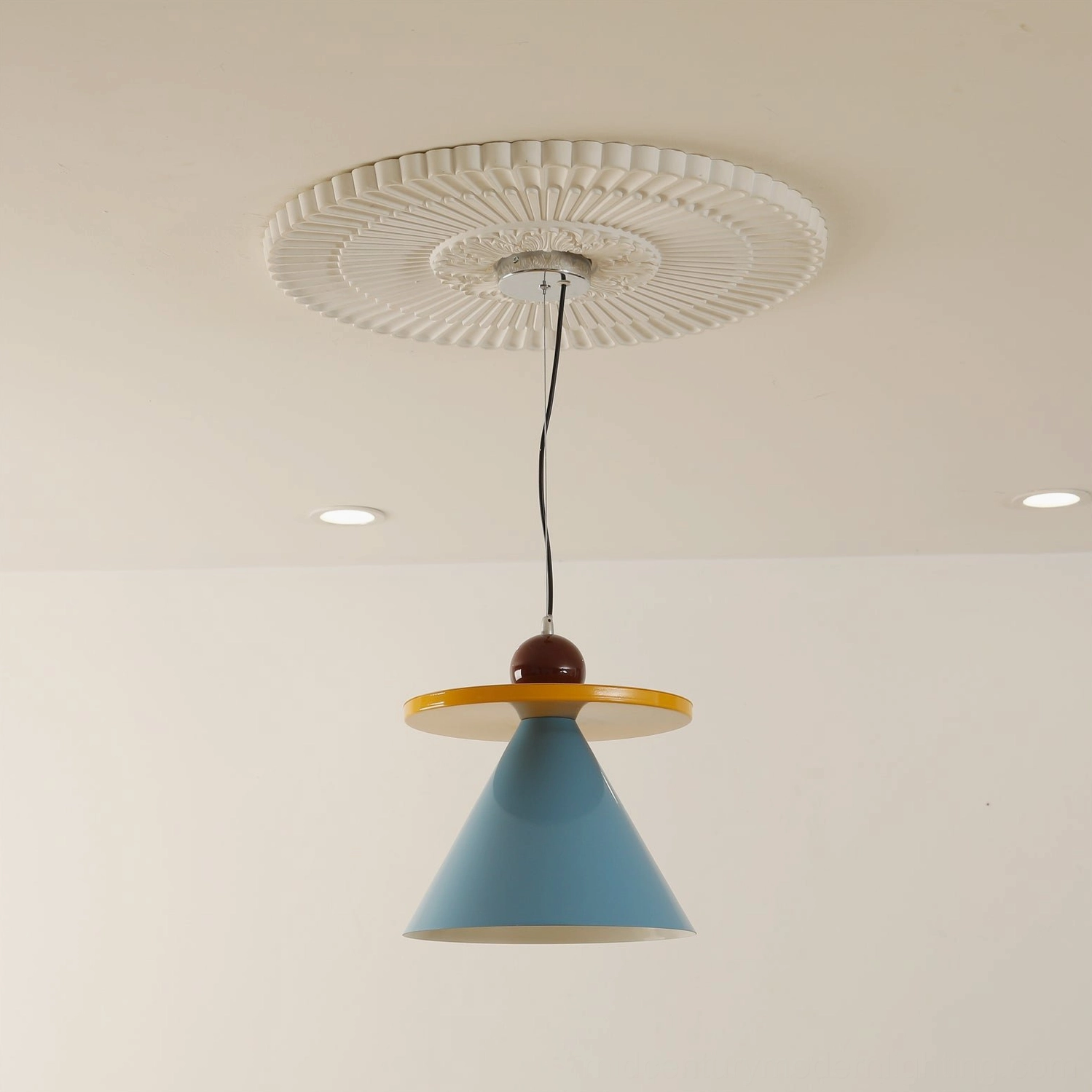 Solid blue cone pendant lamp hanging from residential ceiling with recessed lights, minimalist modern design