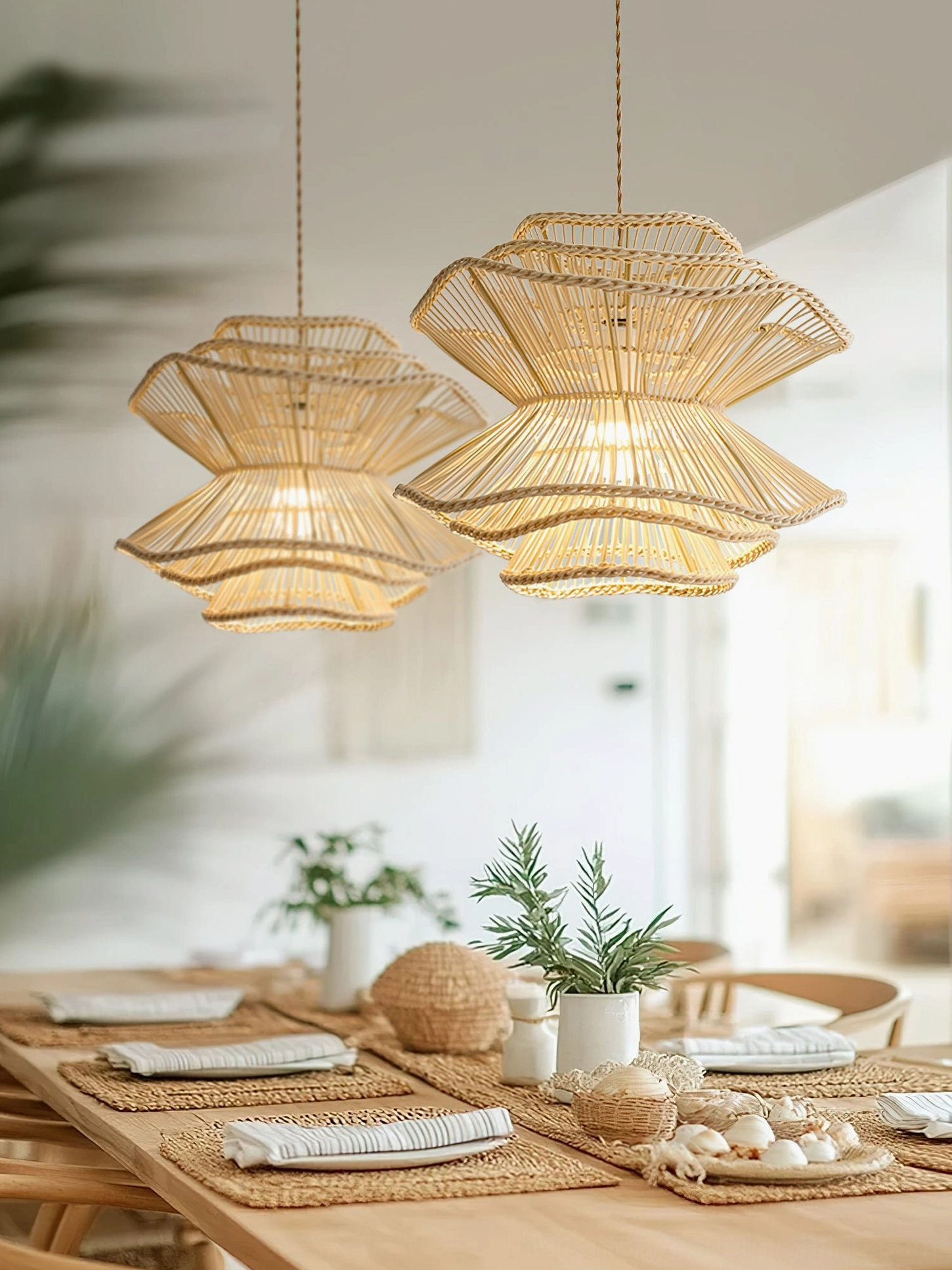 Pair of Sombra handcrafted rattan pendant lights over farmhouse wooden dining table with woven placemats, creating warm ambient lighting