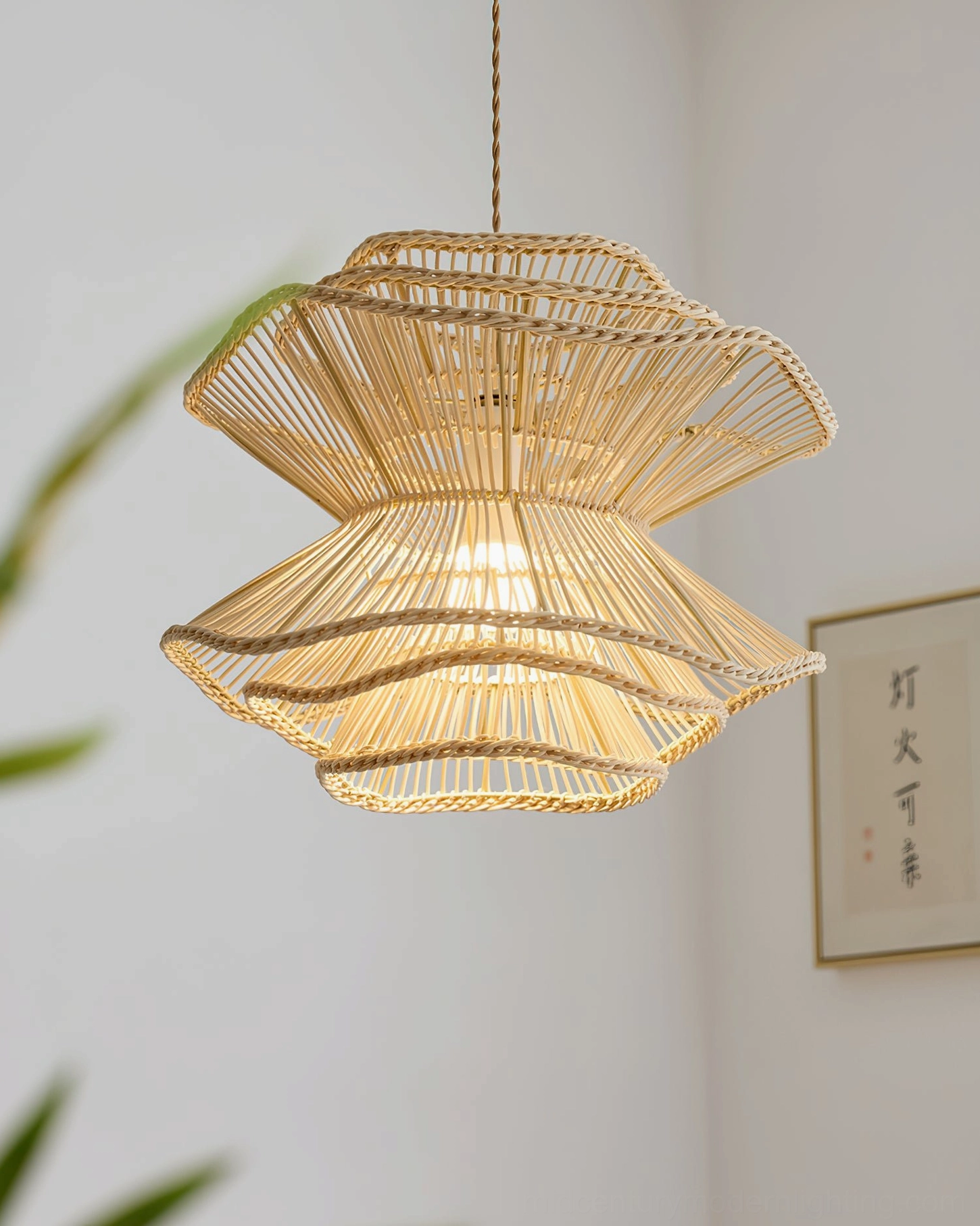 Sombra layered rattan pendant lamp in minimalist space with green foliage, side hanging view showcasing natural bohemian warmth