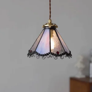 Overhead three-quarter angle view of Sonoma pendant lamp illuminated with warm light against grey wall, Tiffany style stained glass ceiling fixture