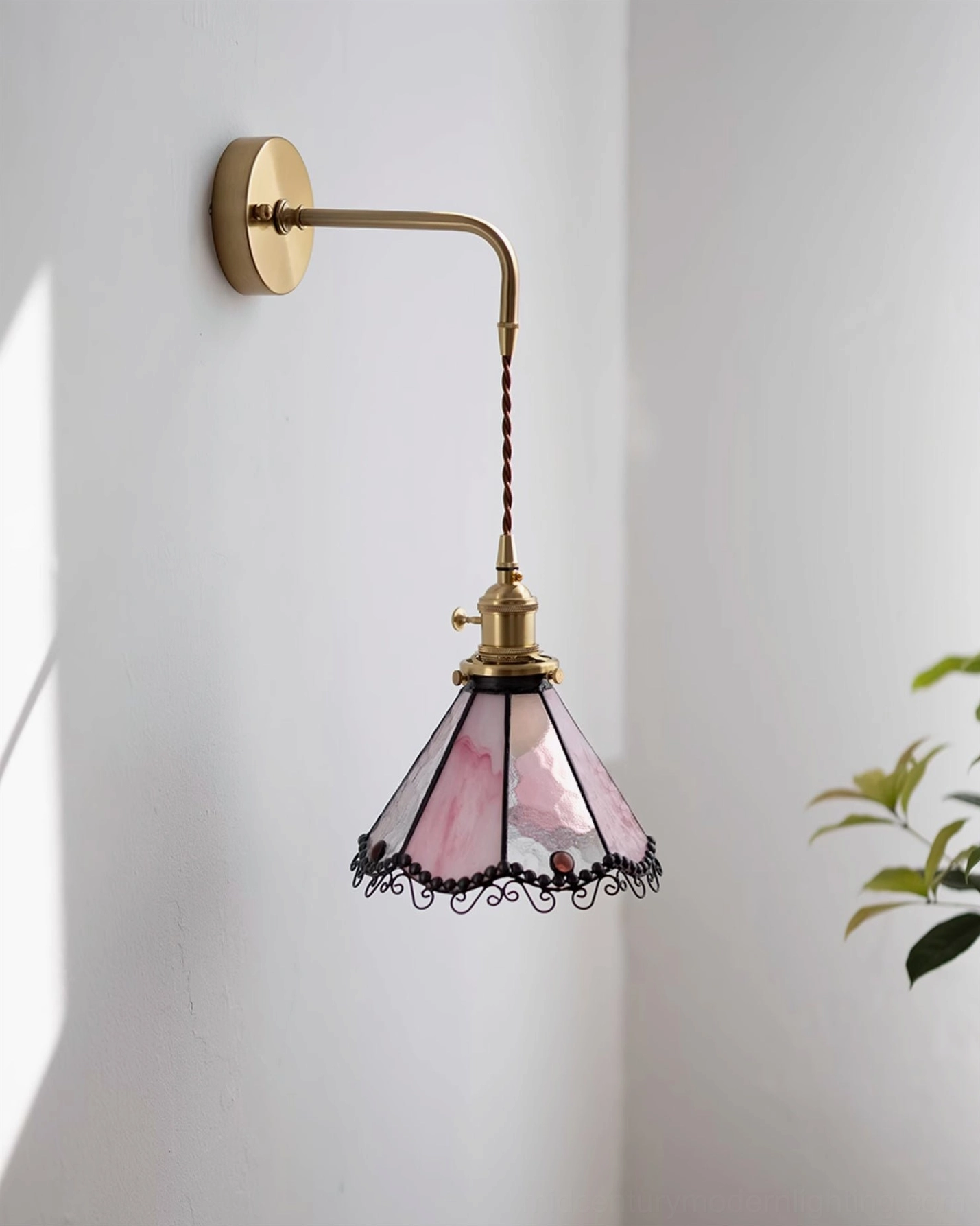 Sonoma Tiffany wall light in pink and white stained glass with long brass-gold arm and black scrollwork trim, sunlit indoor wall