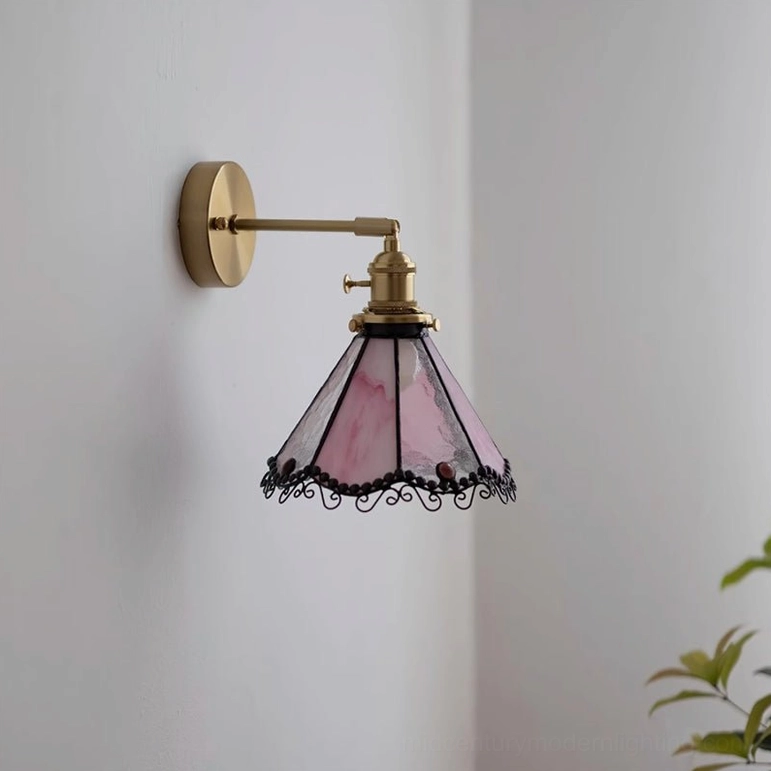 Sonoma Tiffany pink stained glass wall sconce with brass wall mount and decorative scrollwork trim, side frontal view