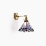 Sonoma Tiffany wall sconce with purple and blue stained glass panels, brass-gold hardware, and ornate black scrollwork detailing, side frontal view
