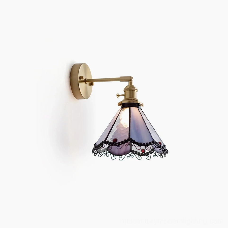 Sonoma Tiffany wall sconce with purple and blue stained glass panels, brass-gold hardware, and ornate black scrollwork detailing, side frontal view