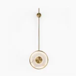 Sorle alabaster wall lamp front view, brushed gold finish with luminous stone disc mounted on slender iron rod
