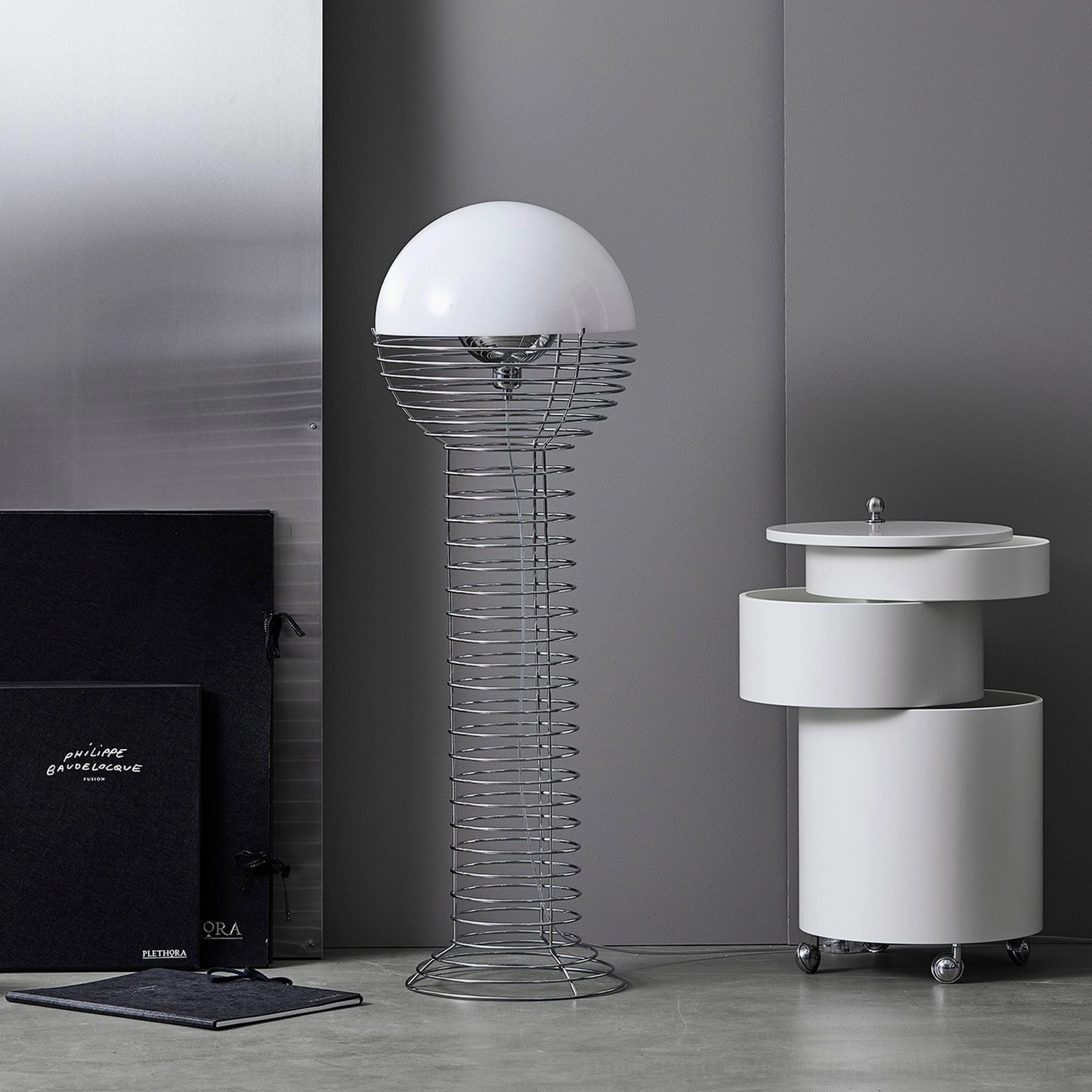Spiral wire floor lamp paired with white rolling side cabinet in minimalist grey wall home interior