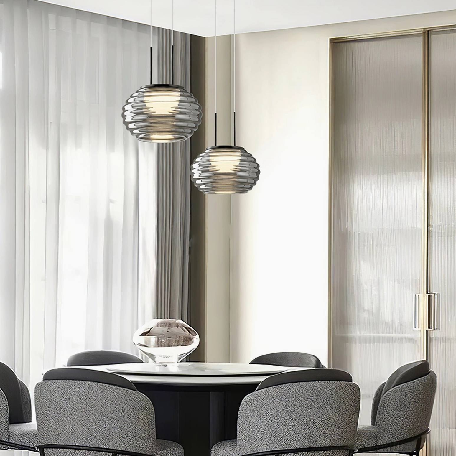 Dual Splugen smoke glass pendant lights above modern dining table with grey chairs, minimalist interior design