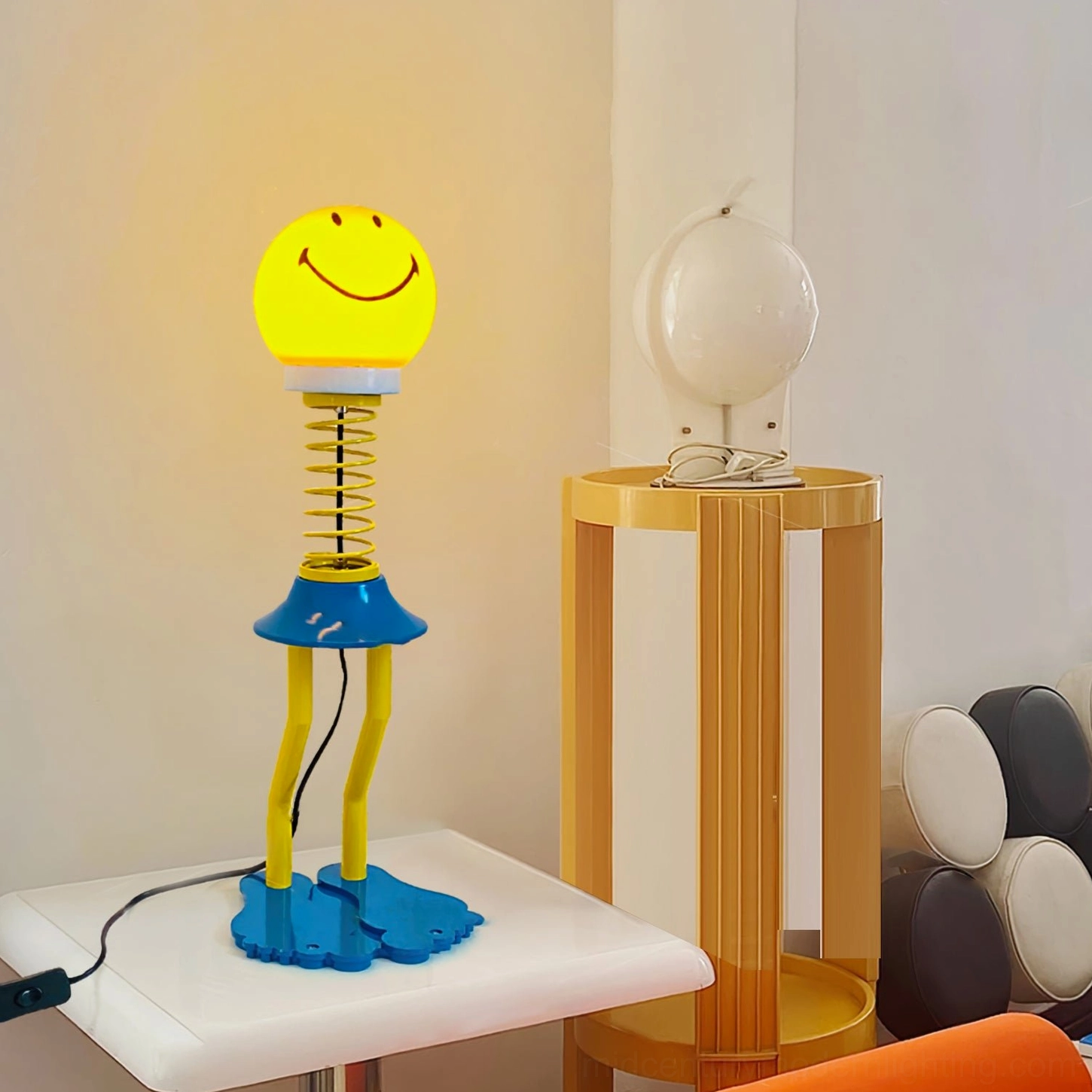 Spiral spring smiley lamp three-quarter perspective on side table with decorative objects, living room corner setting