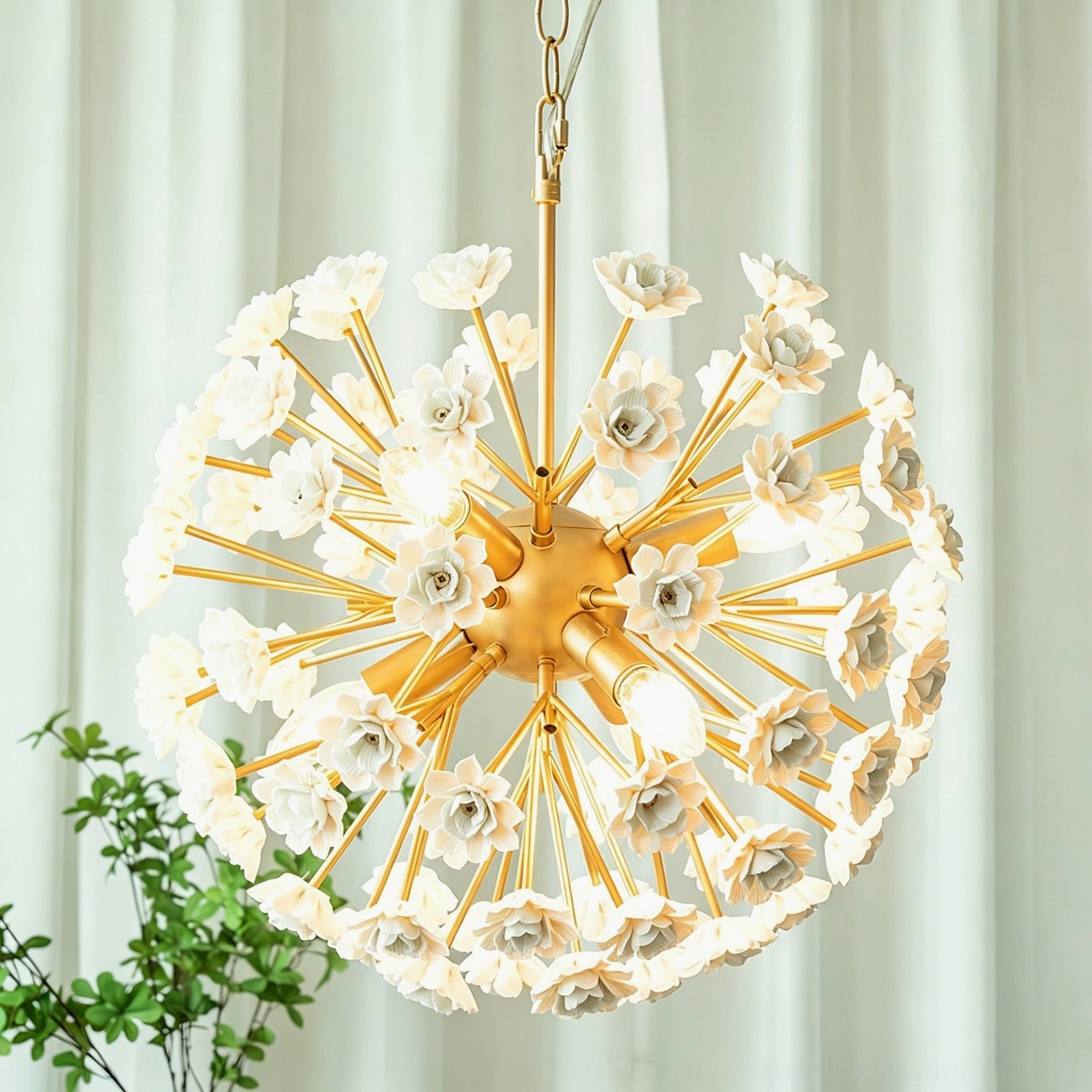 Brass gold floral sputnik chandelier displayed in luxury interior with sheer white curtains and green foliage