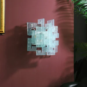 Stagger cast glass sconce mounted on burgundy accent wall with gilt mirror frame and greenery