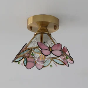 Three-quarter view of butterfly stained glass ceiling light showing colored glass leaves and brass hardware details