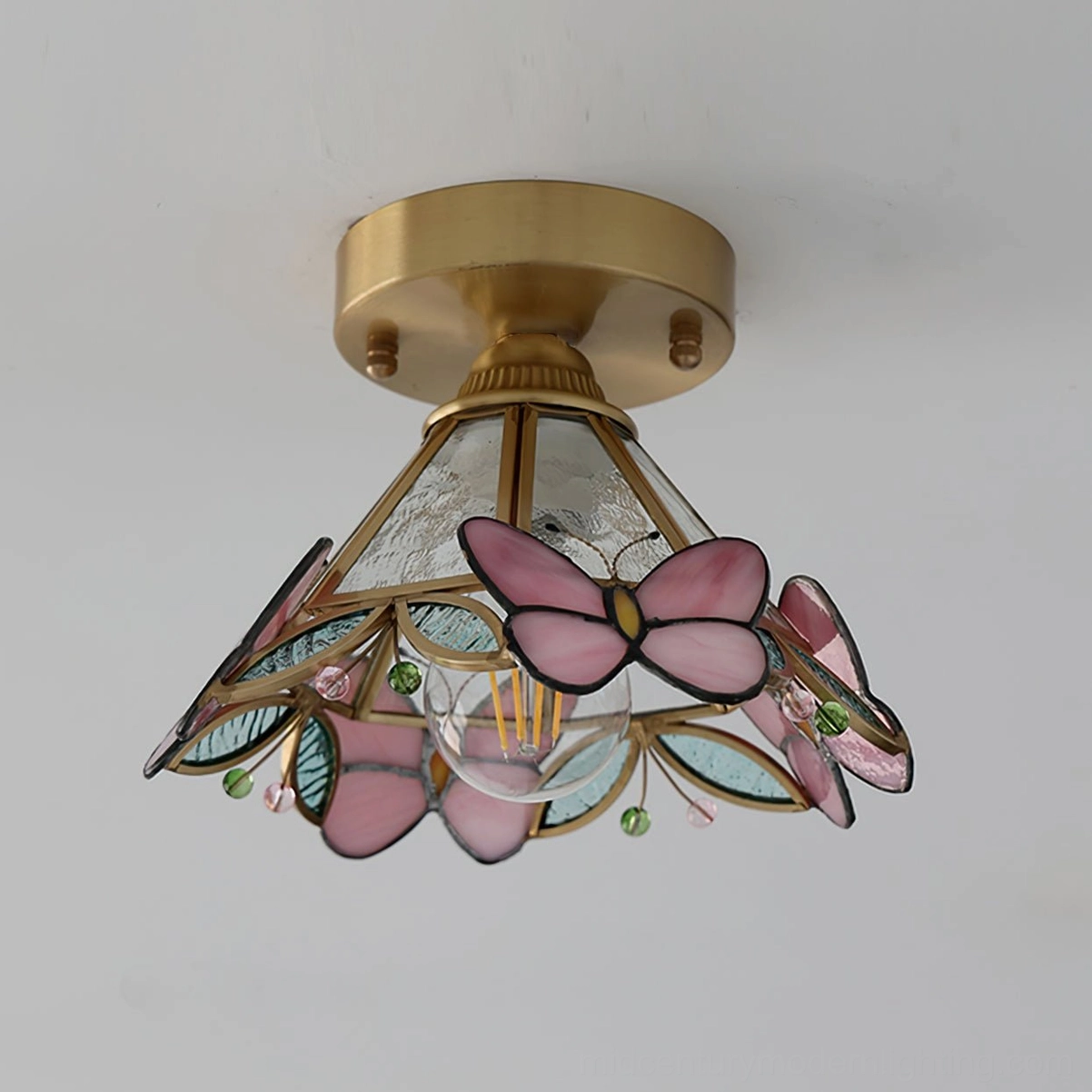 Three-quarter view of butterfly stained glass ceiling light showing colored glass leaves and brass hardware details
