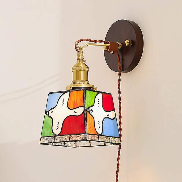 Wall-mounted stained glass dove lamp with dark wood backplate and brass arm installed on indoor wall