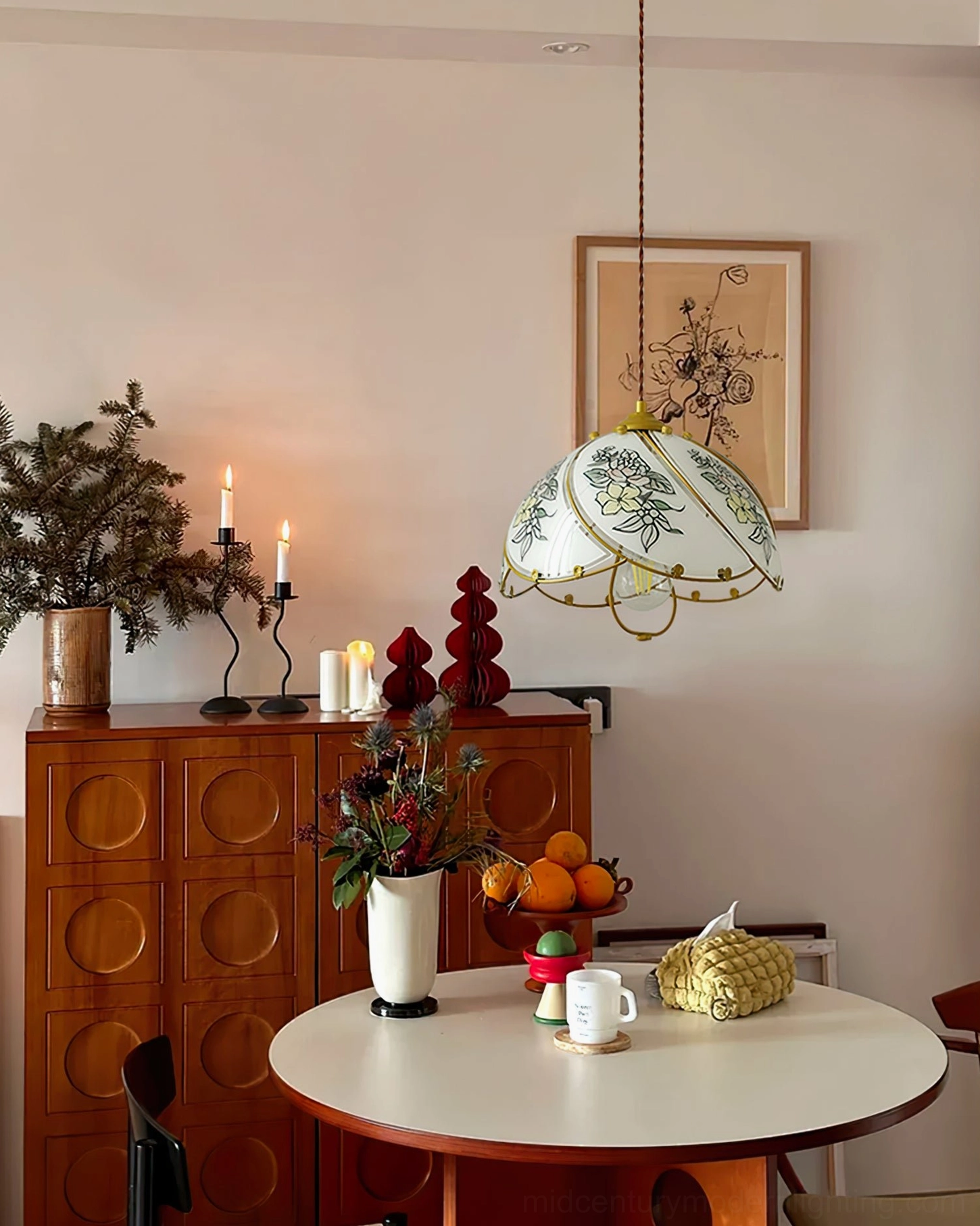 Stained glass lily pendant providing warm ambient light above vintage dining table with candles and fresh fruit decor