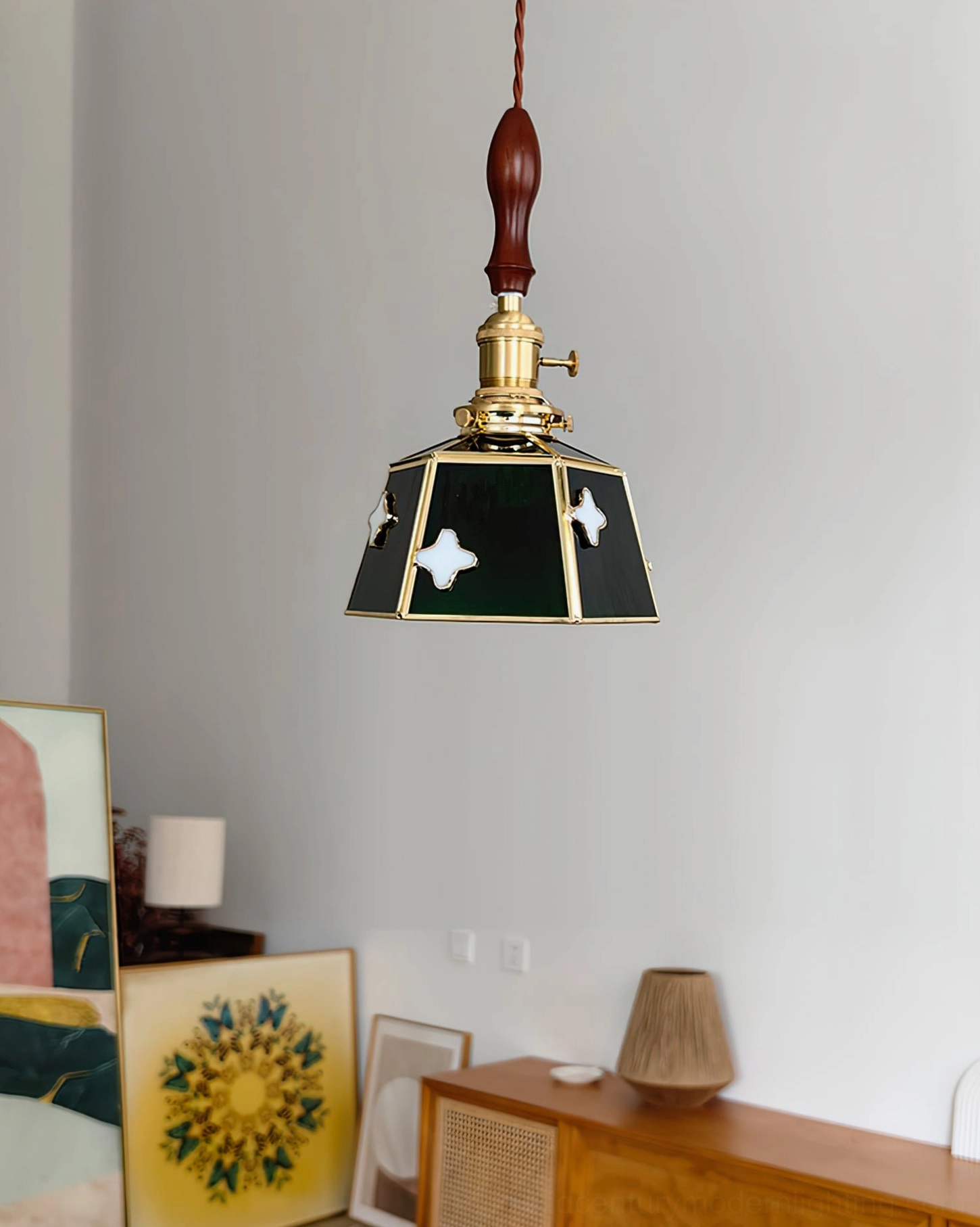 Stained glass pendant lamp with black and green glass featuring white cloud motifs hanging in art-filled living room