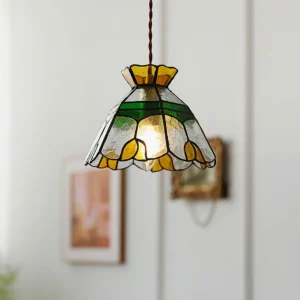 Vitral pendant light illuminated overhead view showing scalloped shade and glowing interior against minimalist wall decor