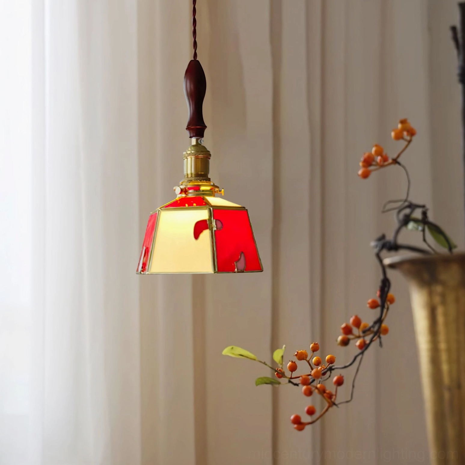 Stained glass pendant lamp with dual-tone red and beige glass shade hanging near sheer curtains and berry decorations