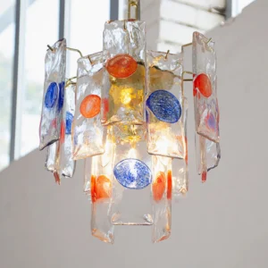 Close-up 3/4 view of artisan pendant lamp showing textured glass slabs and blue orange accents in modern interior setting