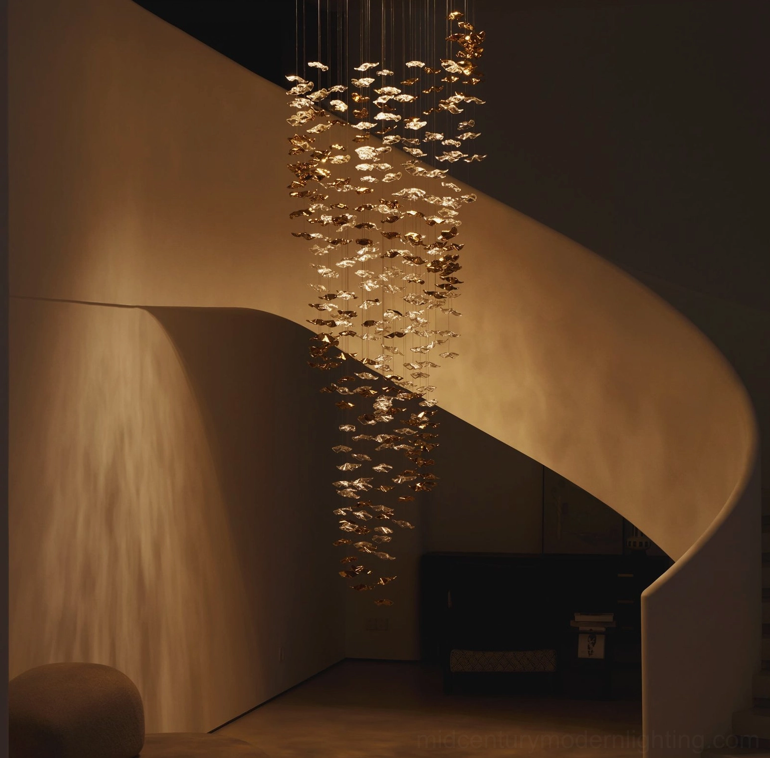 Fluid glass chandelier suspended above luxury villa spiral staircase with warm golden wavy glass pendants