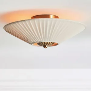 Stefanie ceiling lamp illuminated from below, showing scalloped brass base and warm ambient glow on white ceiling with crown molding