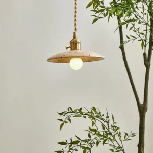 Stella pendant light in botanical living room setting, flat disc travertine shade with exposed Edison bulb and warm wabi-sabi interior styling