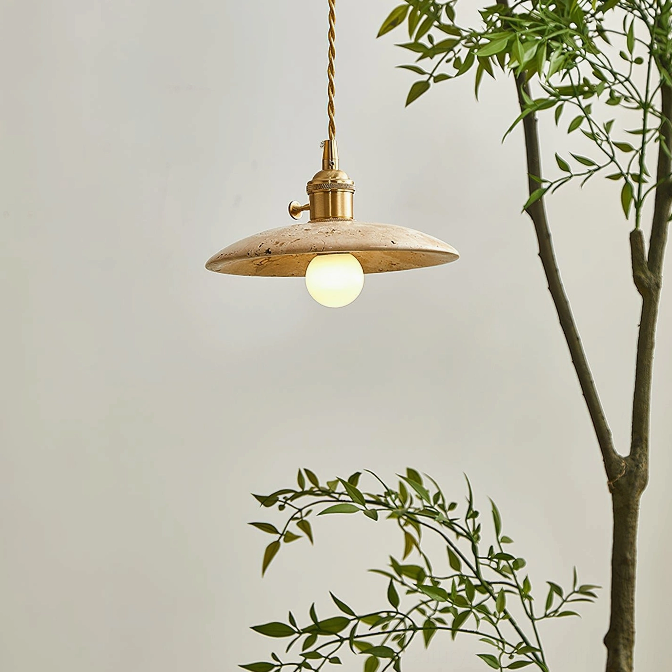Stella pendant light in botanical living room setting, flat disc travertine shade with exposed Edison bulb and warm wabi-sabi interior styling