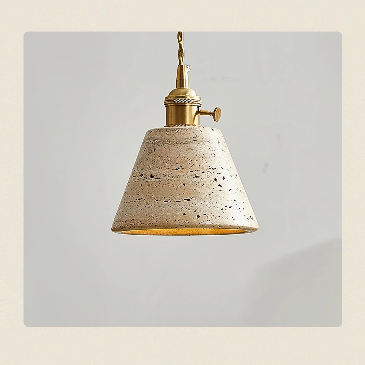 Stella travertine pendant light beauty shot showing the complete fixture with beige stone shade, twisted cord, and polished brass components
