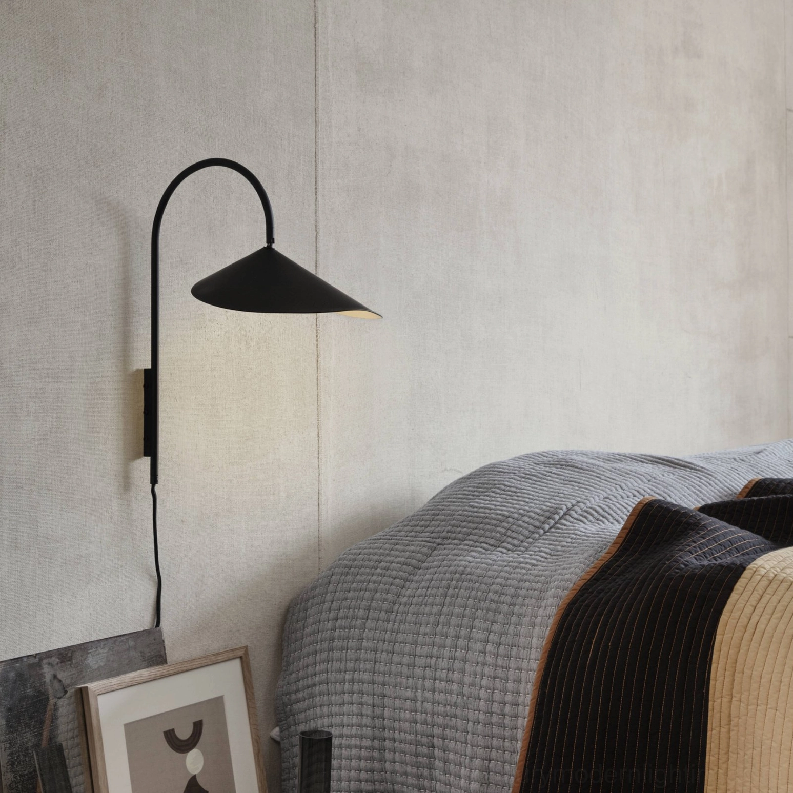 Compact Stella wall lamp in black mounted above bedroom nightstand in modern Scandinavian interior