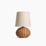 Stellan rattan table lamp with spherical handwoven base and neutral linen fabric shade, front studio view