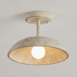 Close-up detail of Stevie ceiling light showing textured weathered resin exterior and exposed Edison bulb through ribbed shade
