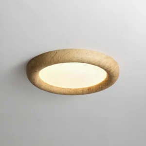 Close-up detail of warm LED glow through frosted acrylic diffuser on stone texture flush mount