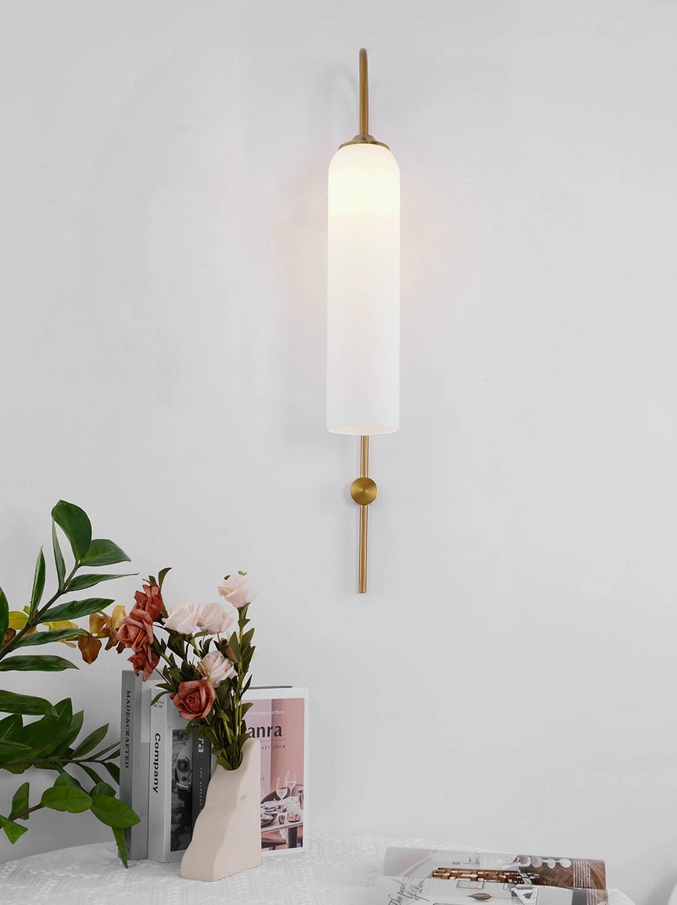 Mid-century modern wall sconce with straight brass rod and single gold accent detail in styled interior