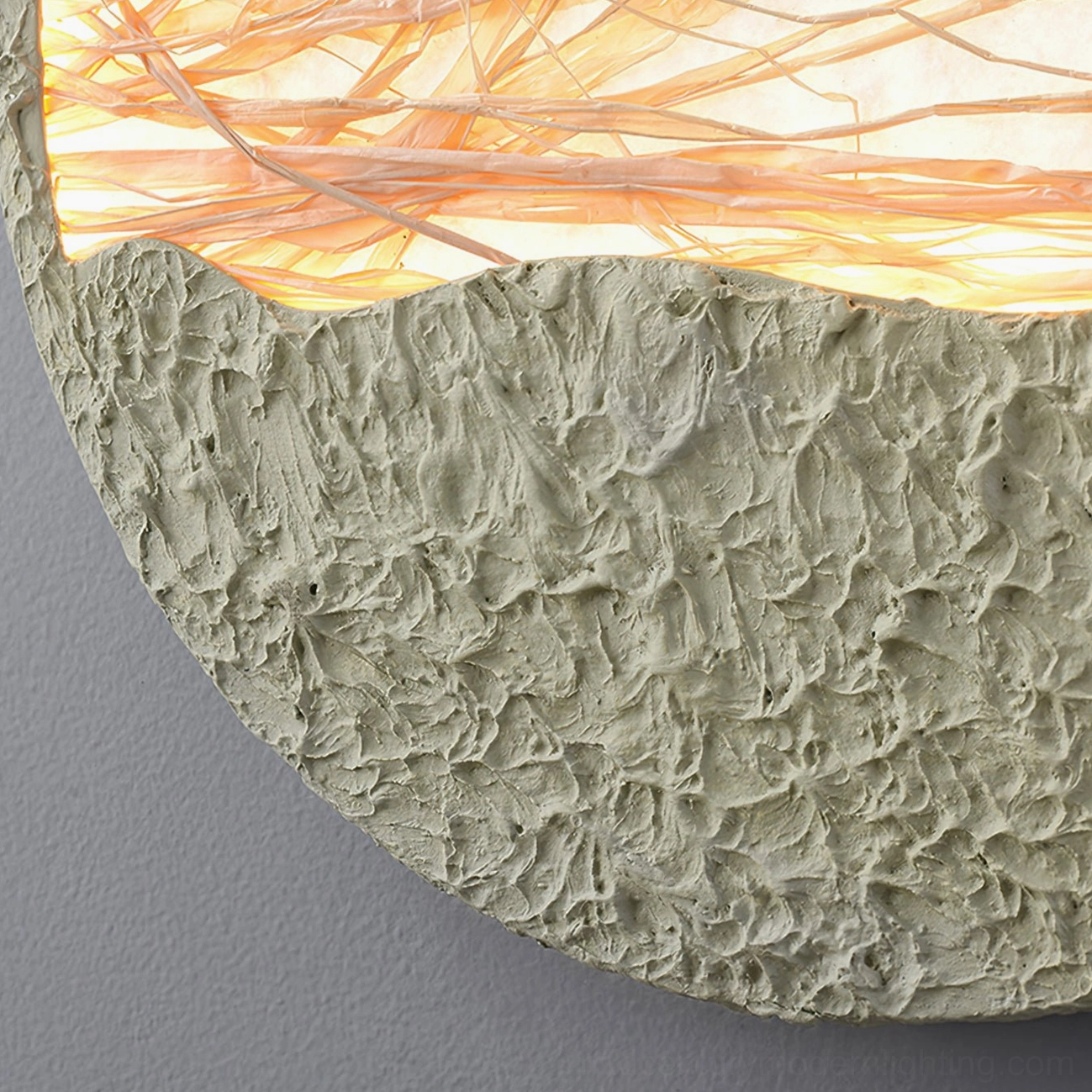 Close-up low-angle view of straw wall lamp showing rough textured green base and woven straw construction details