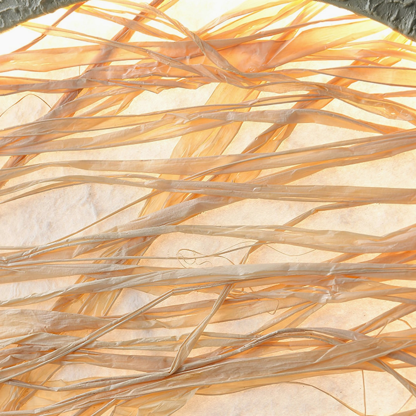 Extreme close-up of natural straw fibers in wall lamp shade - interwoven dried straw strands with light transmission effect
