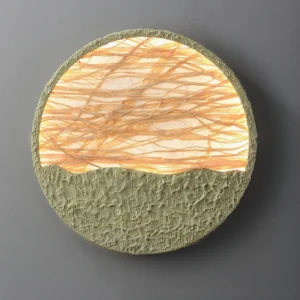 Illuminated straw wall lamp mounted on gray wall - warm light diffusing through woven straw fibers creating ambient glow