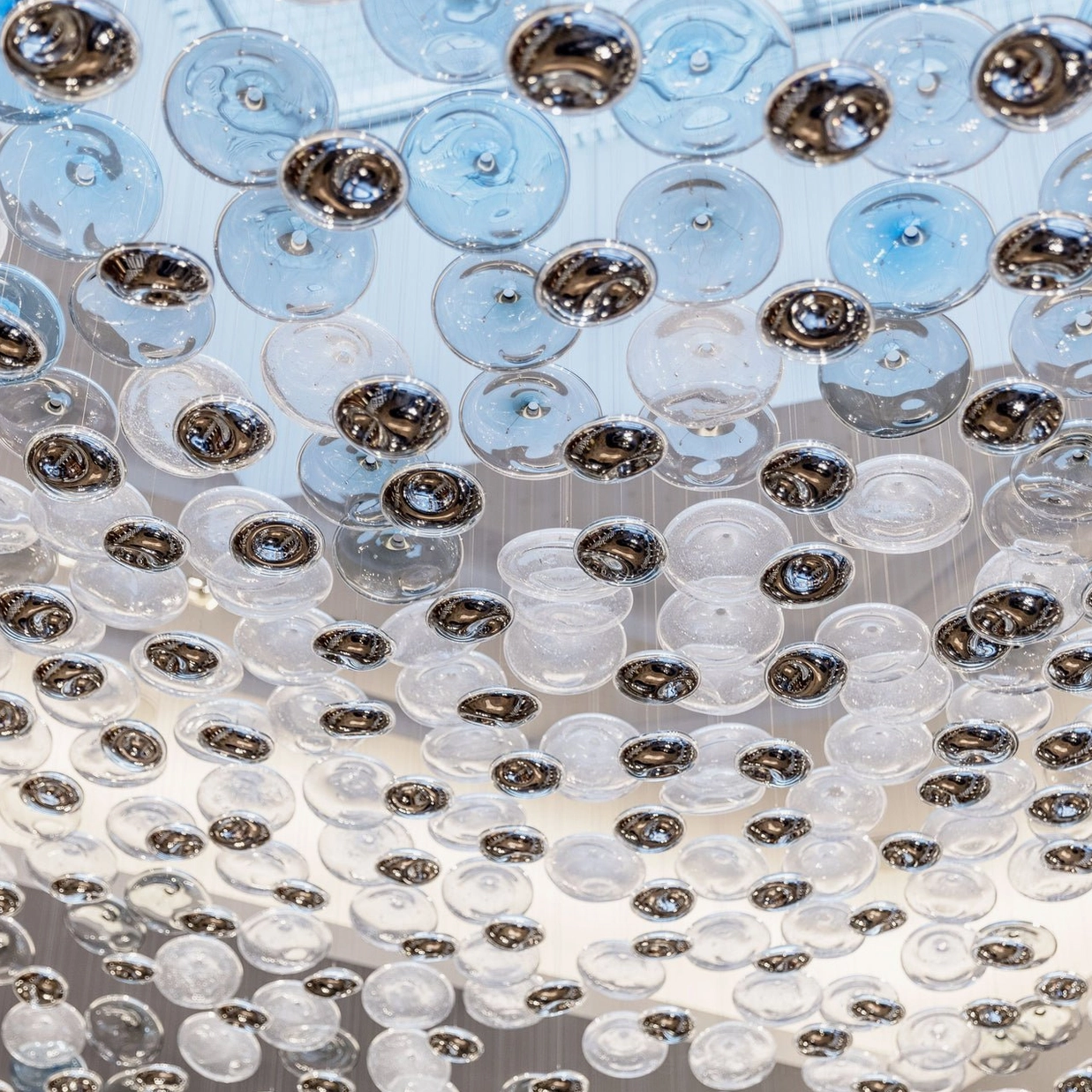 Close-up detail of Surge Glass Cloud Chandelier - mixed blue and clear glass orbs with metallic mounting hardware