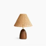 Suri rattan table lamp with woven natural rattan shade and walnut wood pedestal base on white background, front view