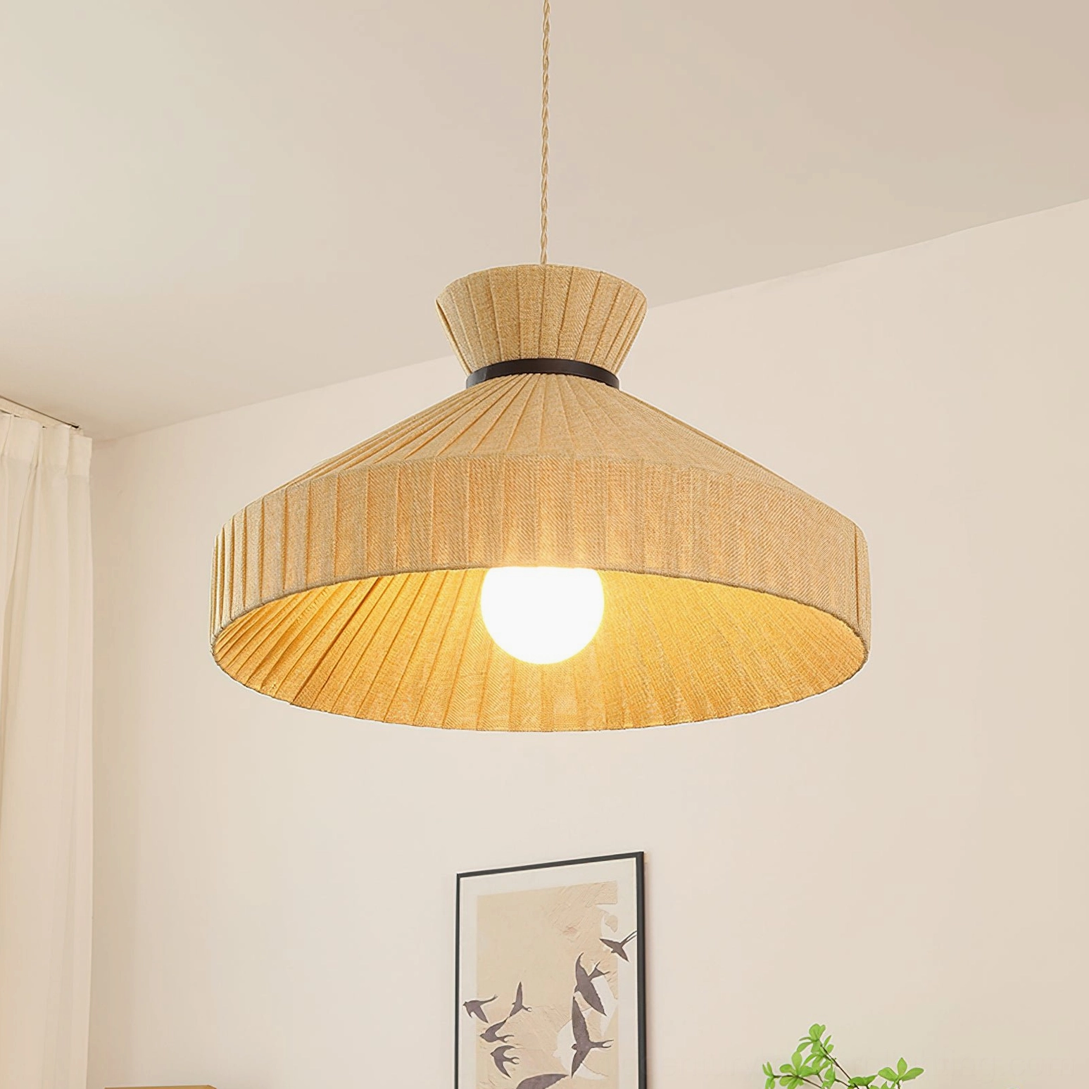 Large Surora pendant light with wide pleated shade suspended low angle view, bright warm illumination in corner setting