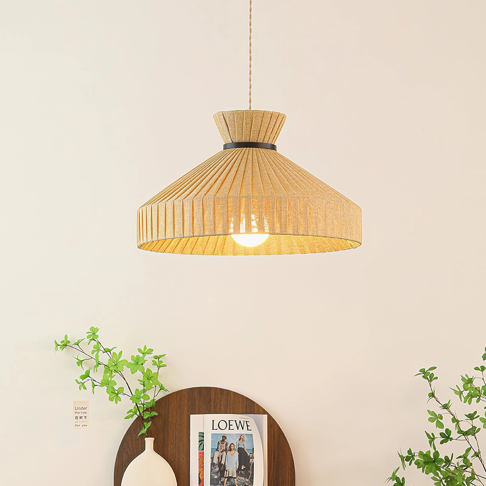 Surora pendant light illuminated with warm glow, overhead view showing black hanging cord and pleated fabric diffusion