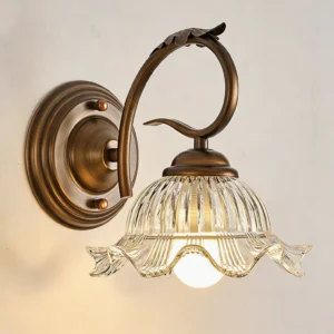 Close-up detail of Sutton wall sconce showing ribbed texture, scalloped rim, and bronze leaf accent on metal arm