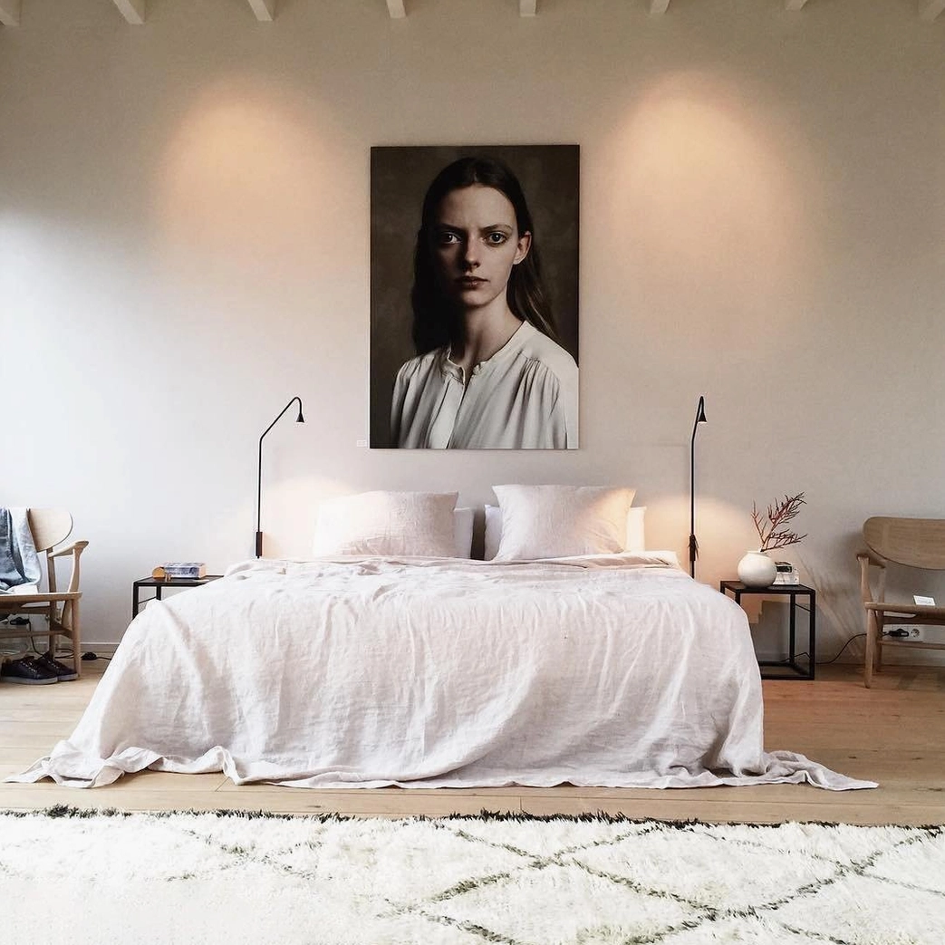 Dual Svarna gold wall sconces in master bedroom with bed and wall art, warm contemporary ambient layered lighting