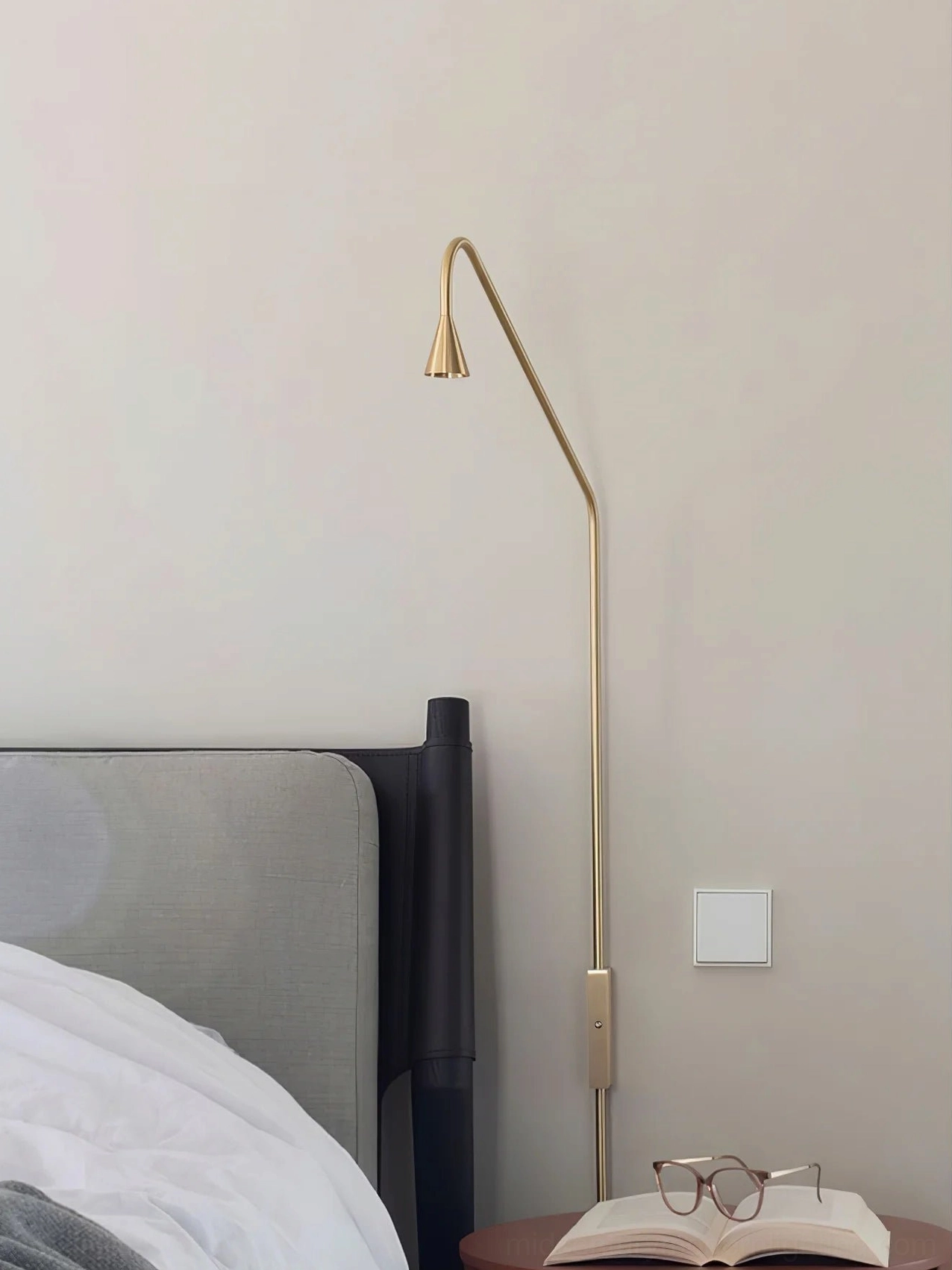 Svarna gold wall sconce close-up bedside positioning, warm minimalist lamp head diffusing light, Nordic design